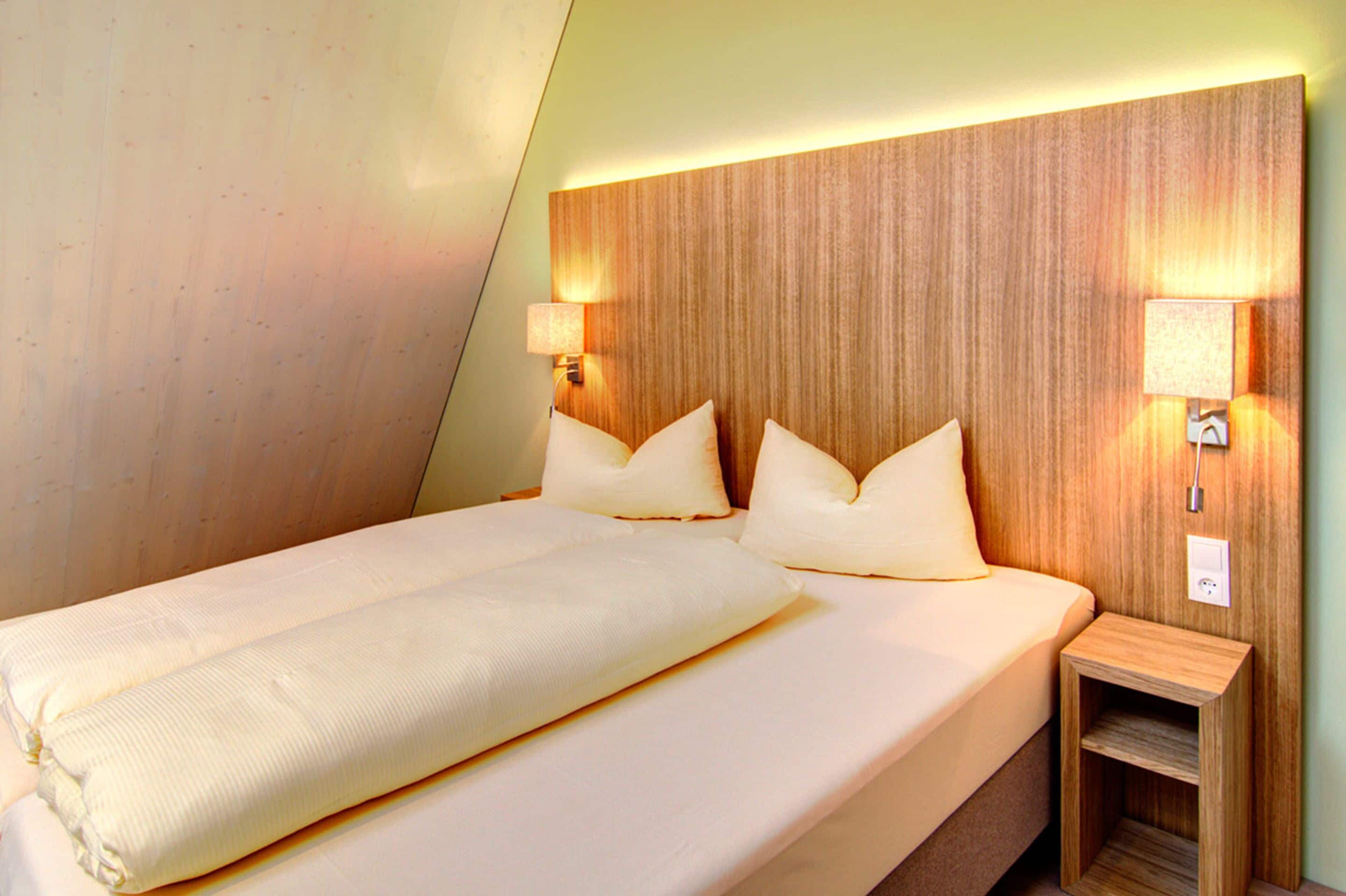 A hotel room with a large bed, two bedside lamps, and a wooden headboard.