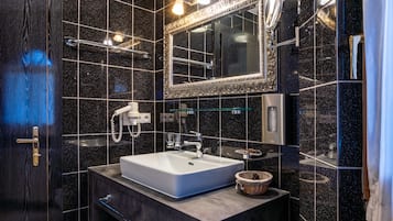 Une salle de bain moderne avec un grand miroir, un lavabo blanc et un porte-serviettes.