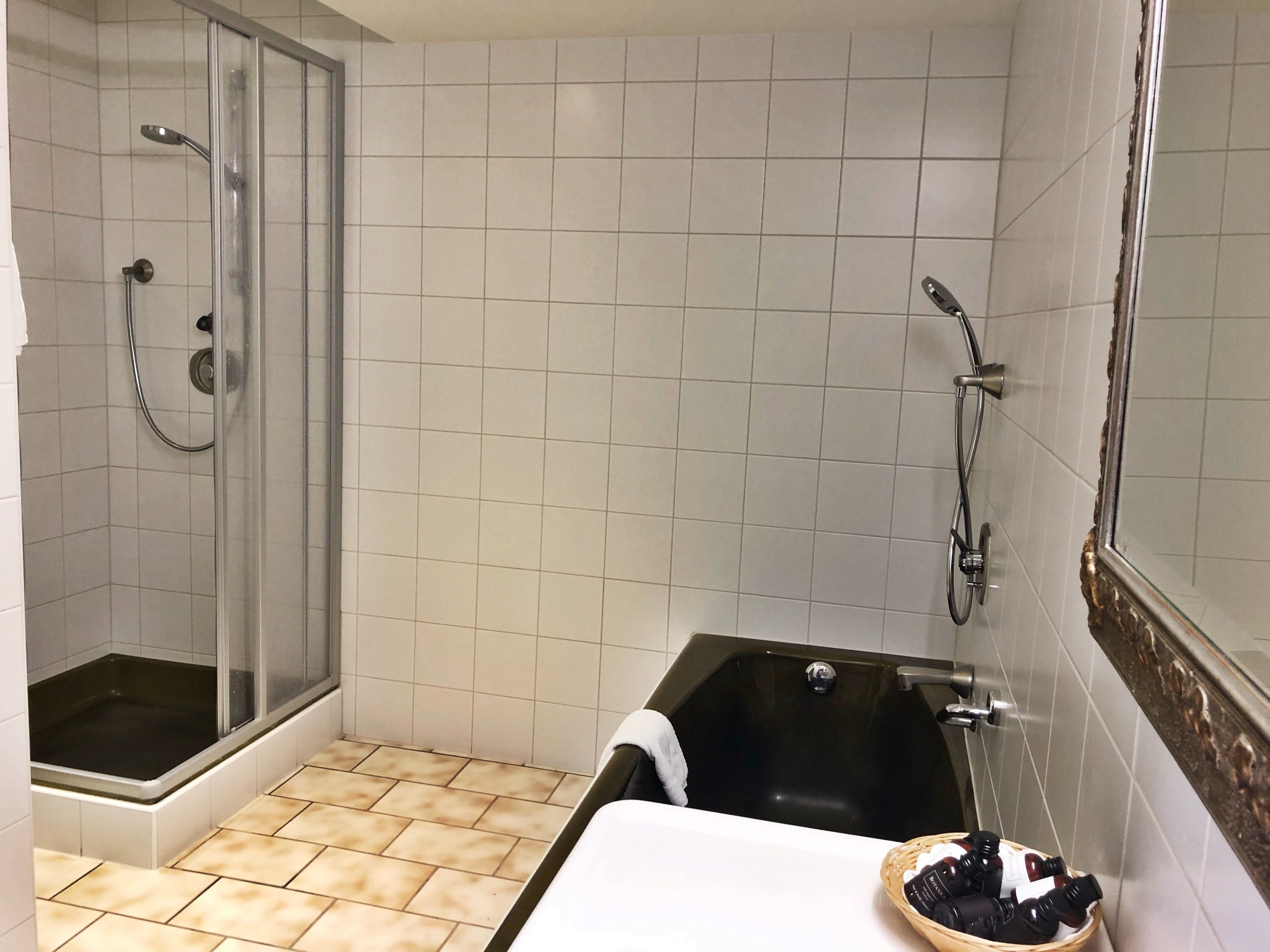 Ein Badezimmer mit einer gläsernen Duschkabine, einer schwarzen Badewanne und einem weißen Waschbecken.