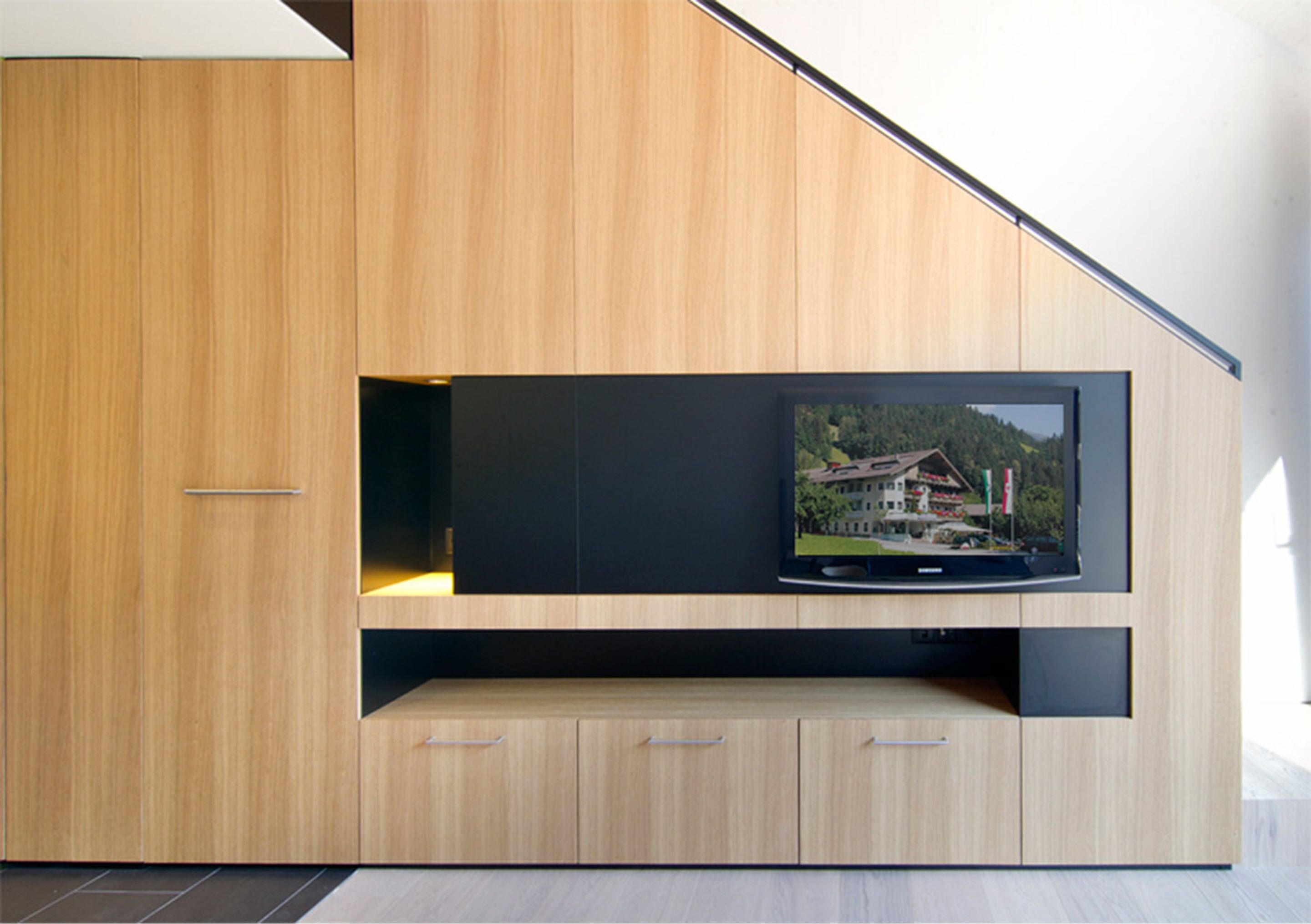 A modern entertainment unit with a flat-screen TV, built-in shelving, and a minimalist design.