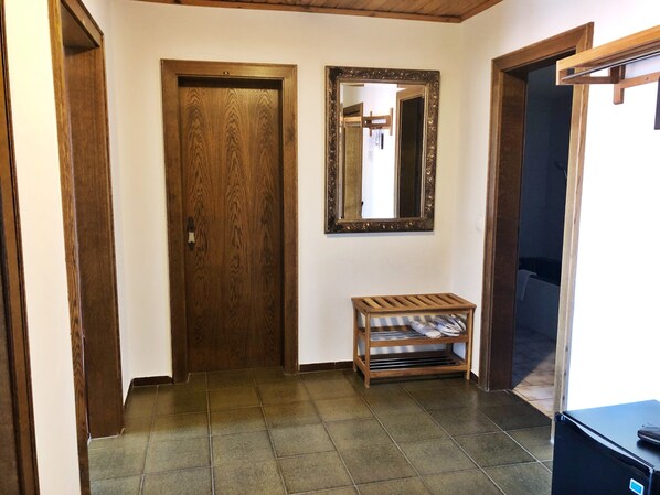 A hallway with a wooden door, a mirror, and a small wooden bench.