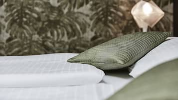 A neatly made bed with a green pillow and white linens.