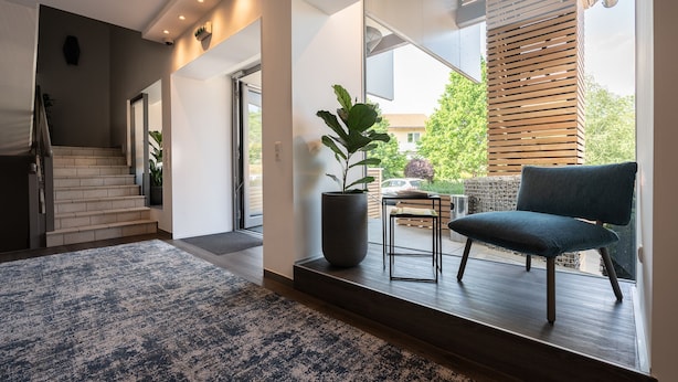A modern interior with a staircase, a large potted plant, a blue chair, and a view of the outside. - Hotel Garni Birkenhof (Bad Radkersburg)