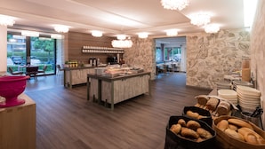 A modern hotel lobby with a central buffet area, seating arrangements, and a view of the outdoors. - Hotel Garni Birkenhof (Bad Radkersburg)
