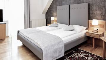 A modern hotel room with a large bed, two bedside tables, a flat-screen TV, and a patterned rug.