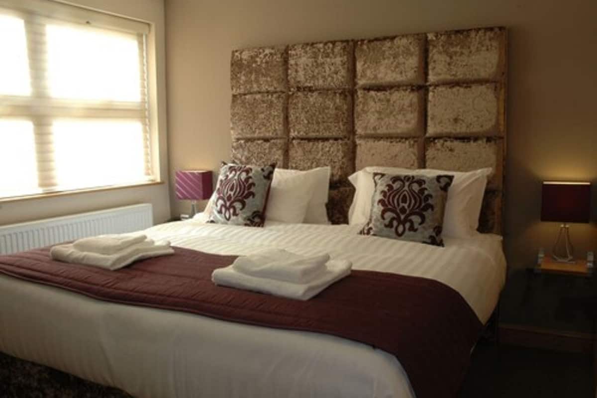 A neatly made bed with a headboard, pillows, and a blanket.