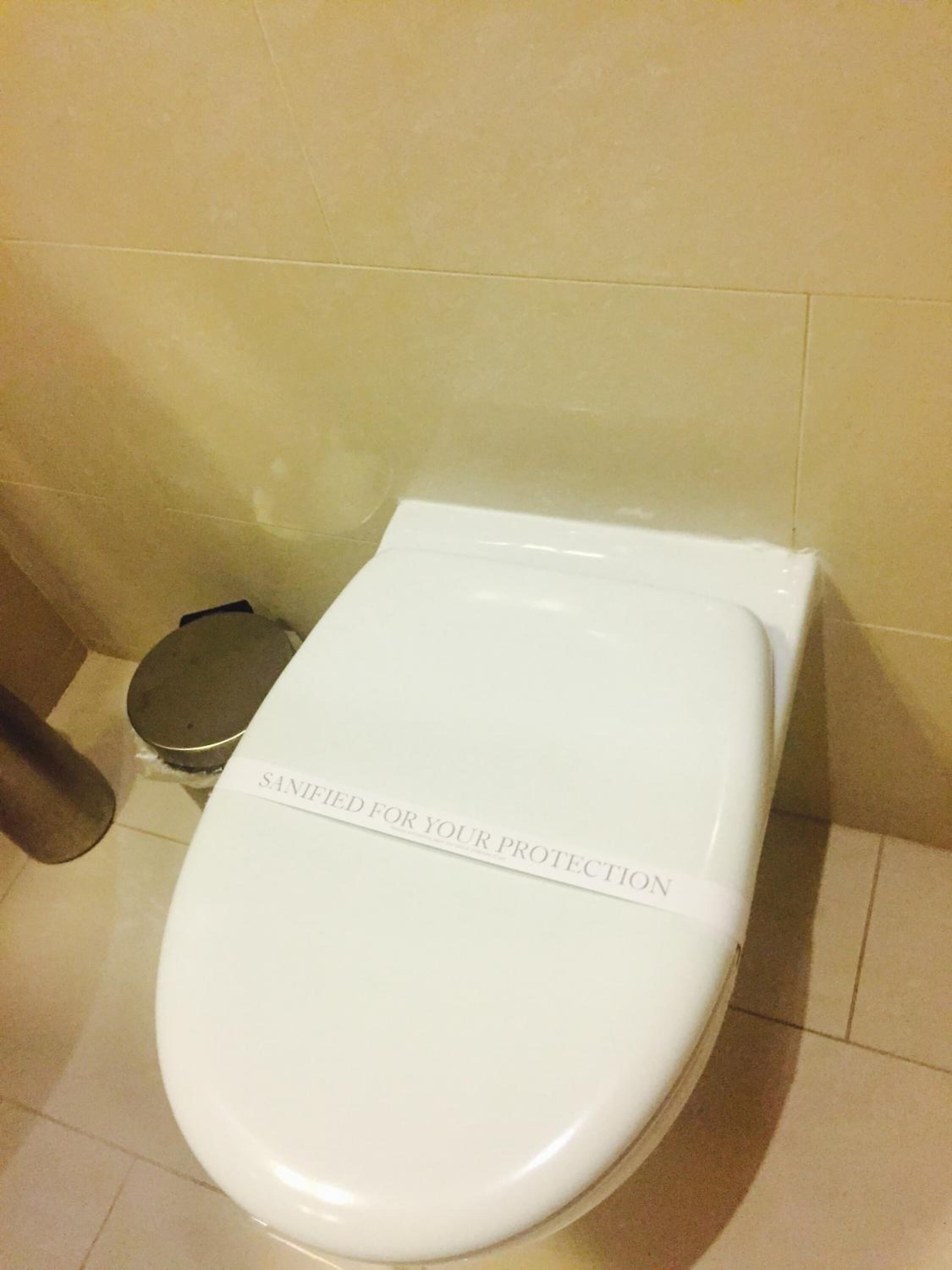 Un inodoro blanco con tapa que muestra la leyenda 'SANITIZED FOR YOUR PROTECTION'.