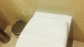 Un inodoro blanco con tapa que muestra la leyenda 'SANITIZED FOR YOUR PROTECTION'.