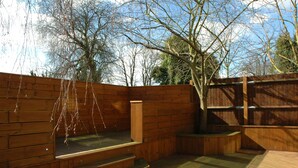 A wooden deck with a built-in hot tub, steps, and a wooden fence. - Homestay Hotel (Hounslow)