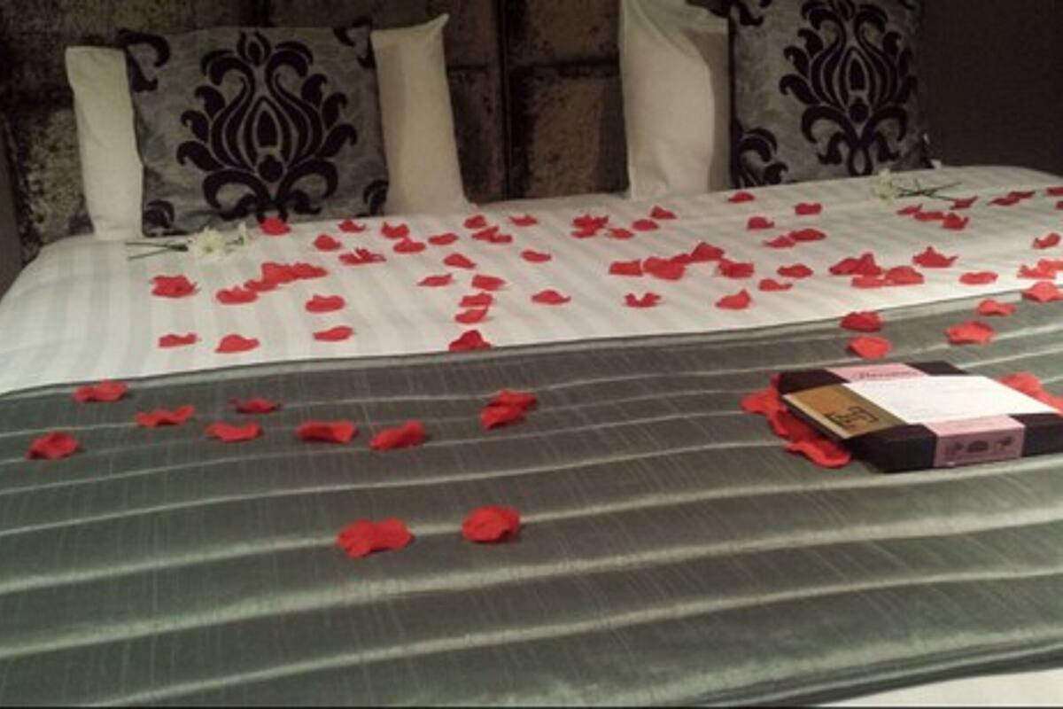 A bed with rose petals and a book, suggesting a romantic setting.