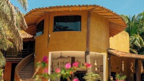 A two-story building with a pool, surrounded by palm trees and pink flowers. - Stevie WonderLand (Díaz)