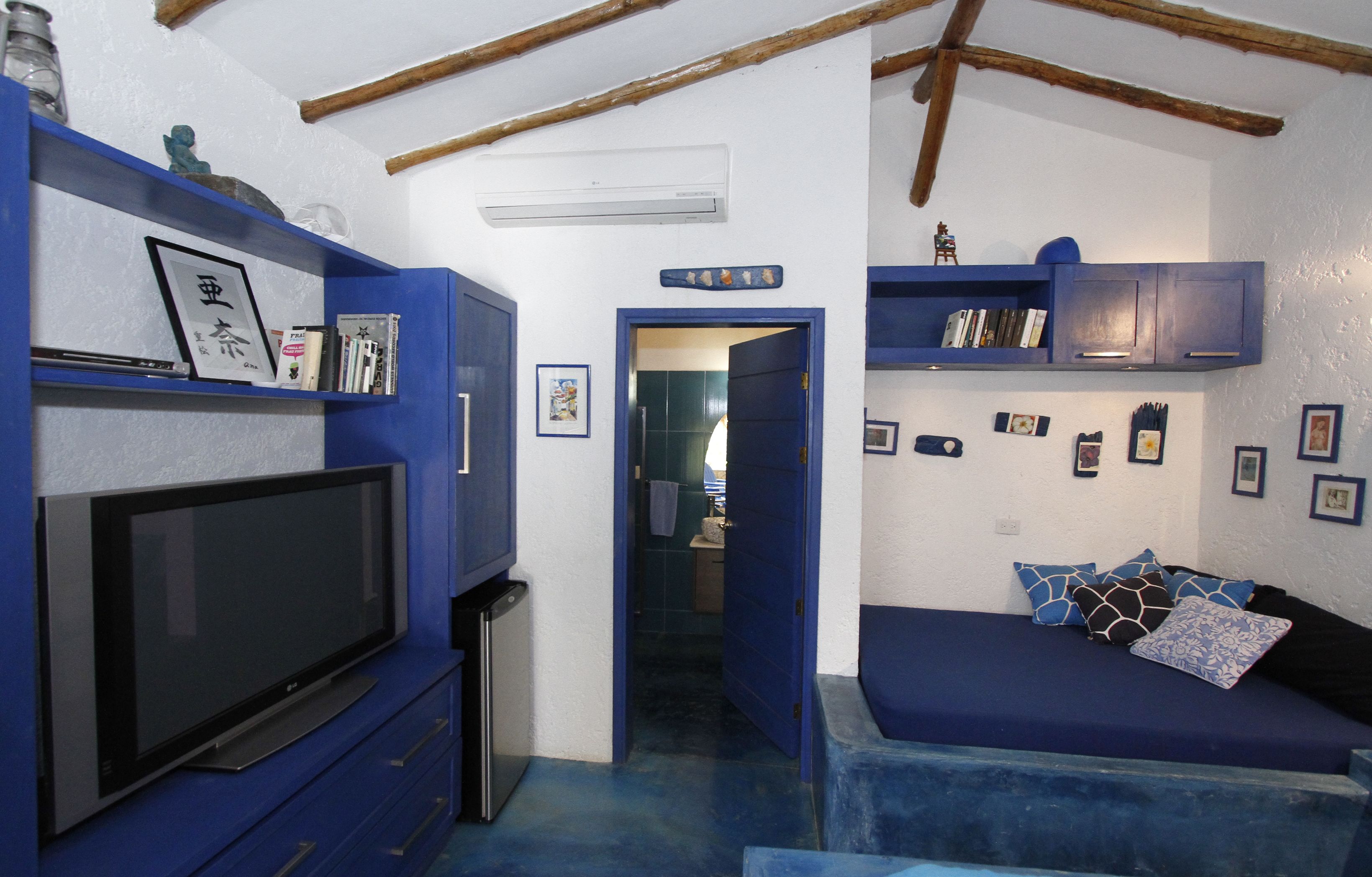 A compact room with a TV, blue furniture, and a door leading to another area.