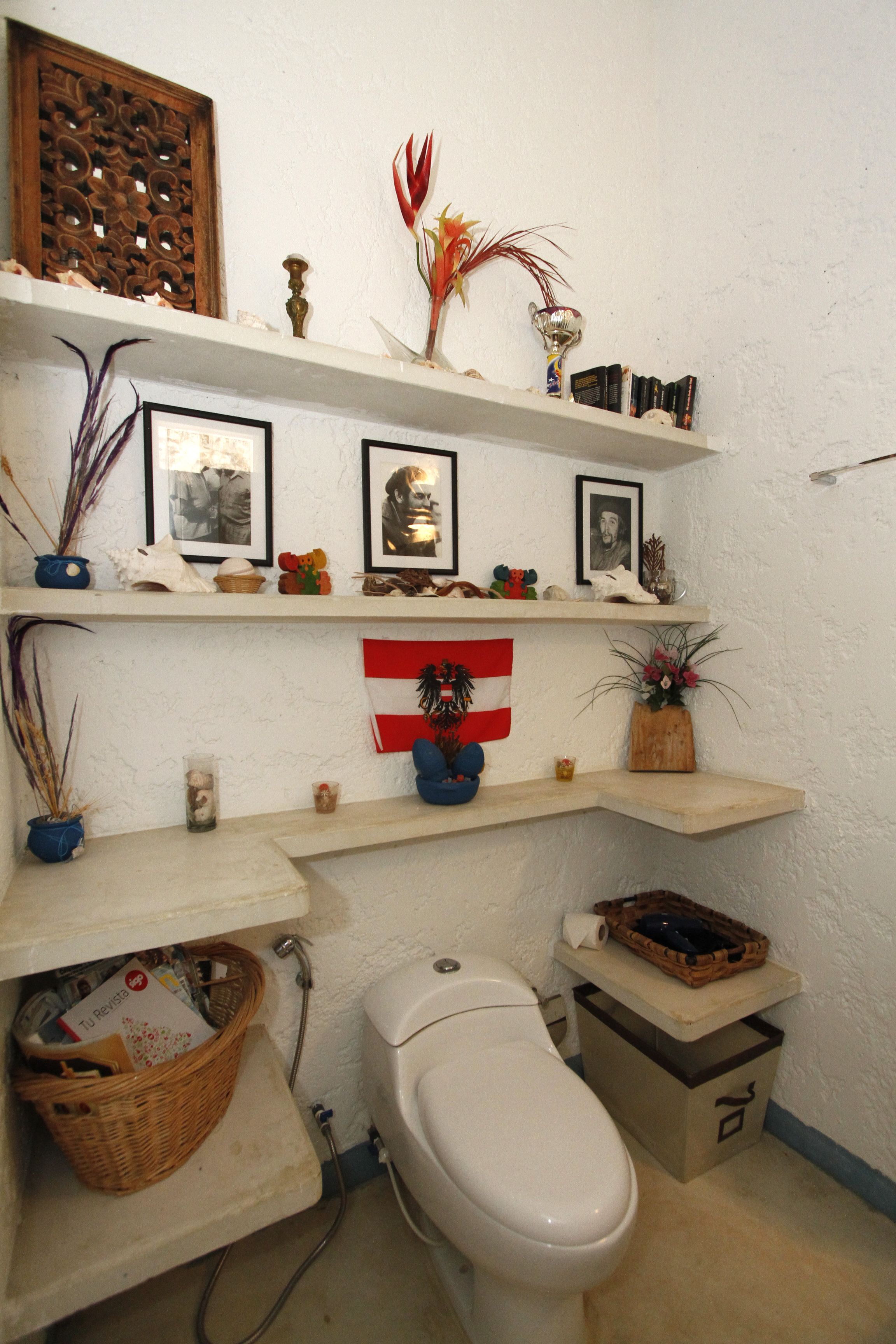 A bathroom with a toilet, shelves with various items, and a flag.