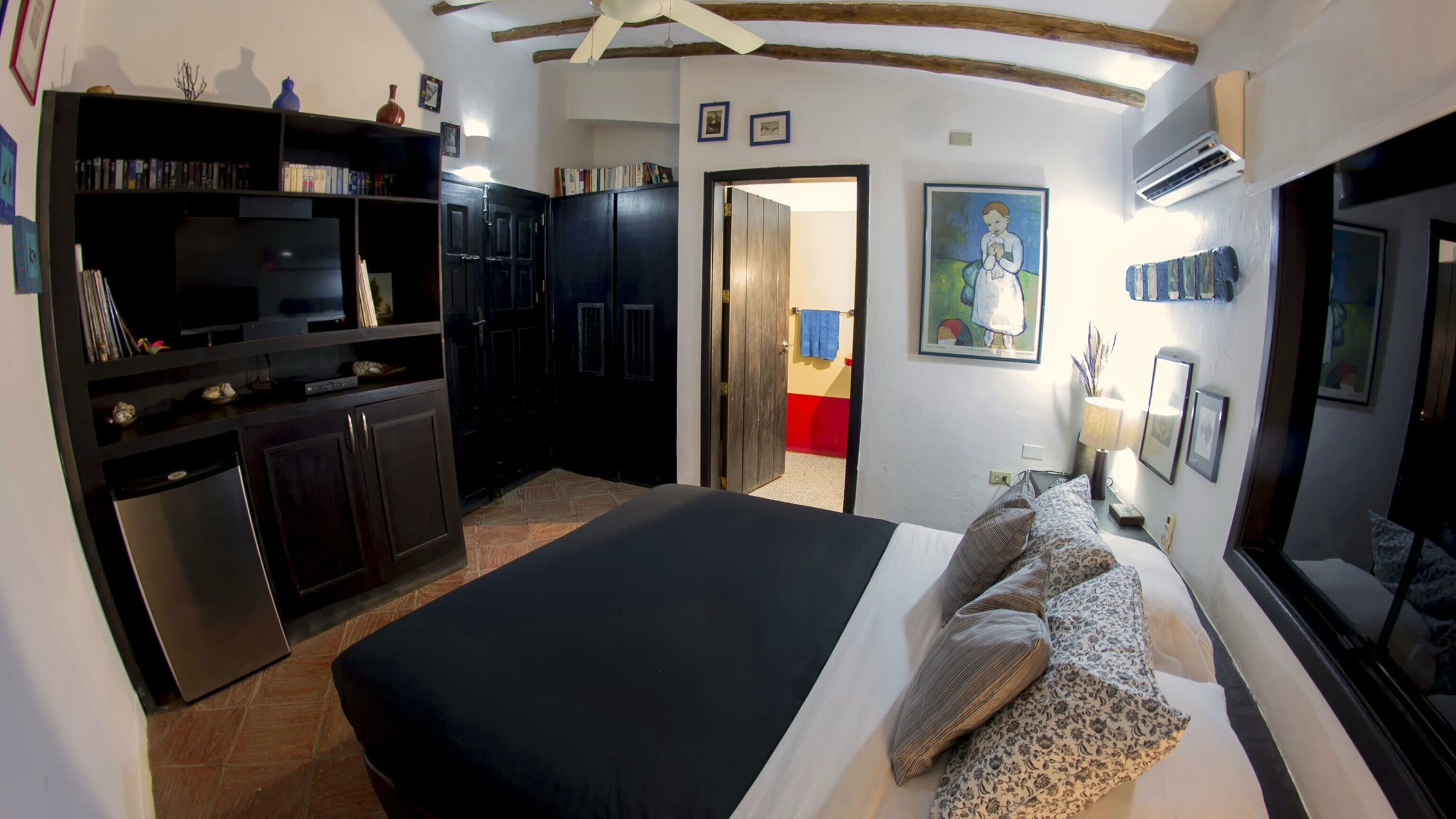 Un dormitorio con cama, armario, escritorio y puerta que da a otra habitación.
