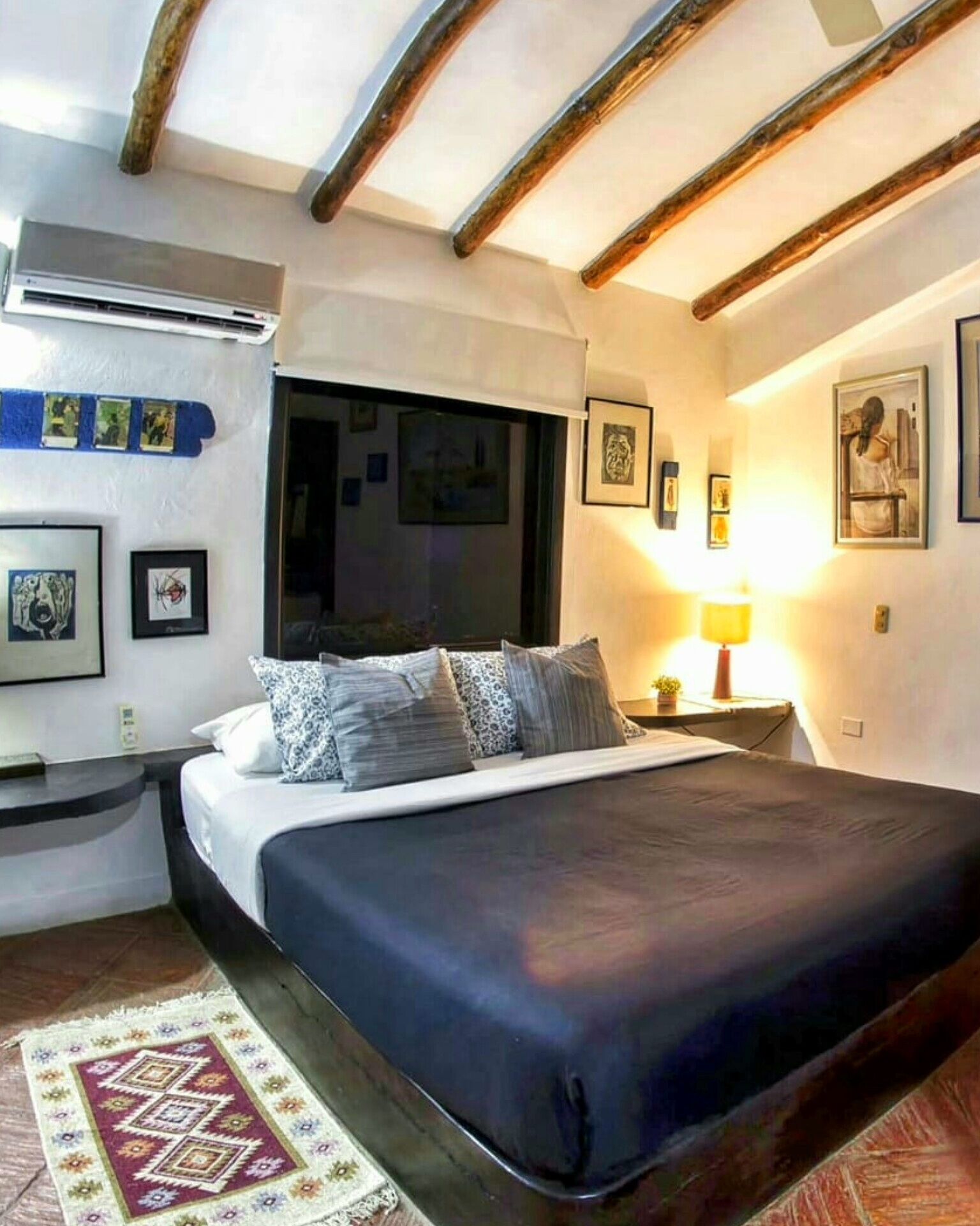 Un dormitorio con una cama grande, una ventana y un techo con vigas a la vista.