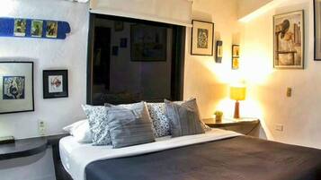 Un dormitorio con una cama grande, una ventana y un techo con vigas a la vista.