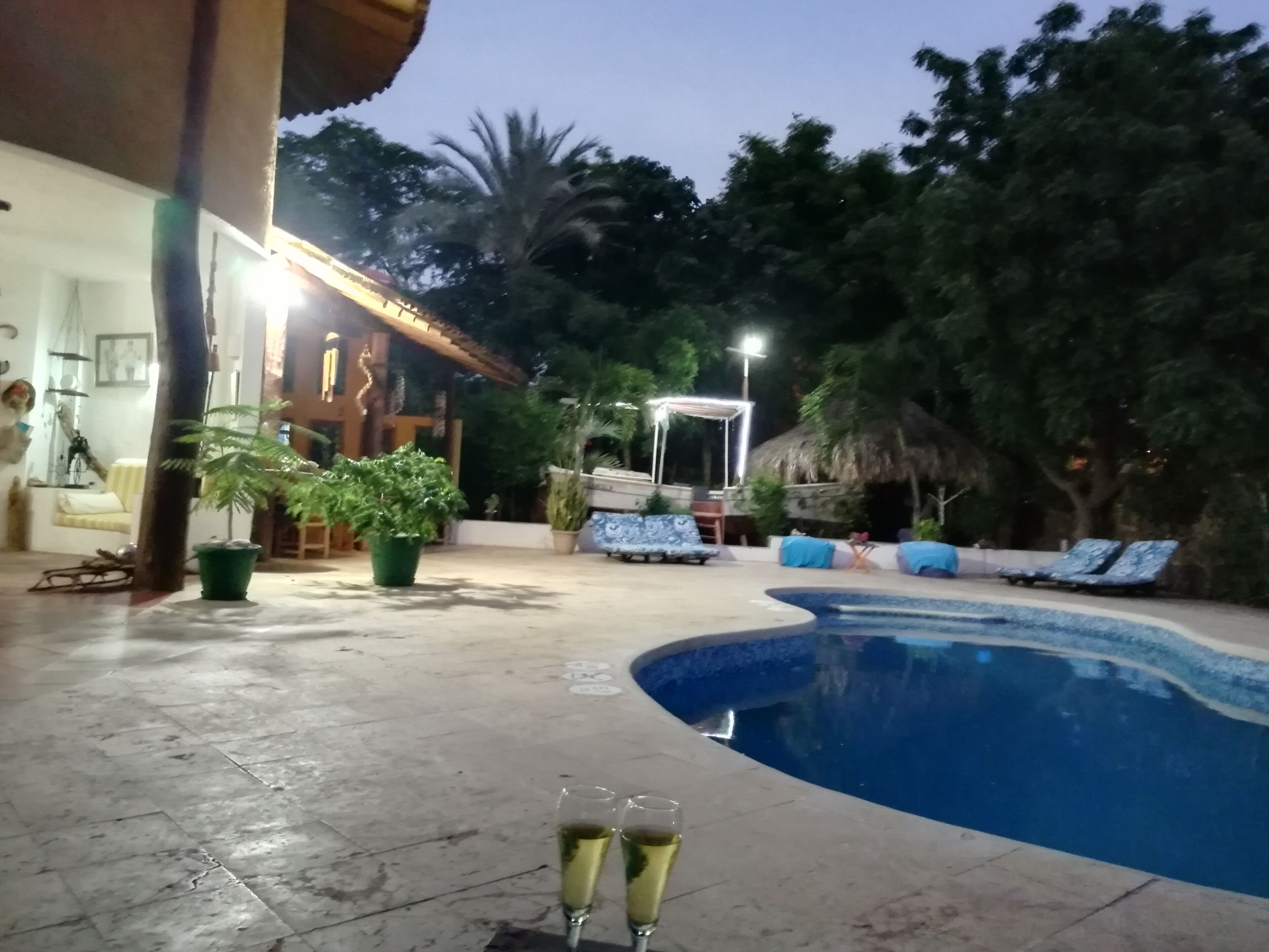 A swimming pool with lounge chairs and a covered seating area.