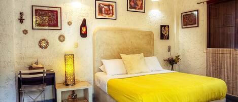 Un dormitorio con cama, mesita de noche, lámpara y adornos en la pared.