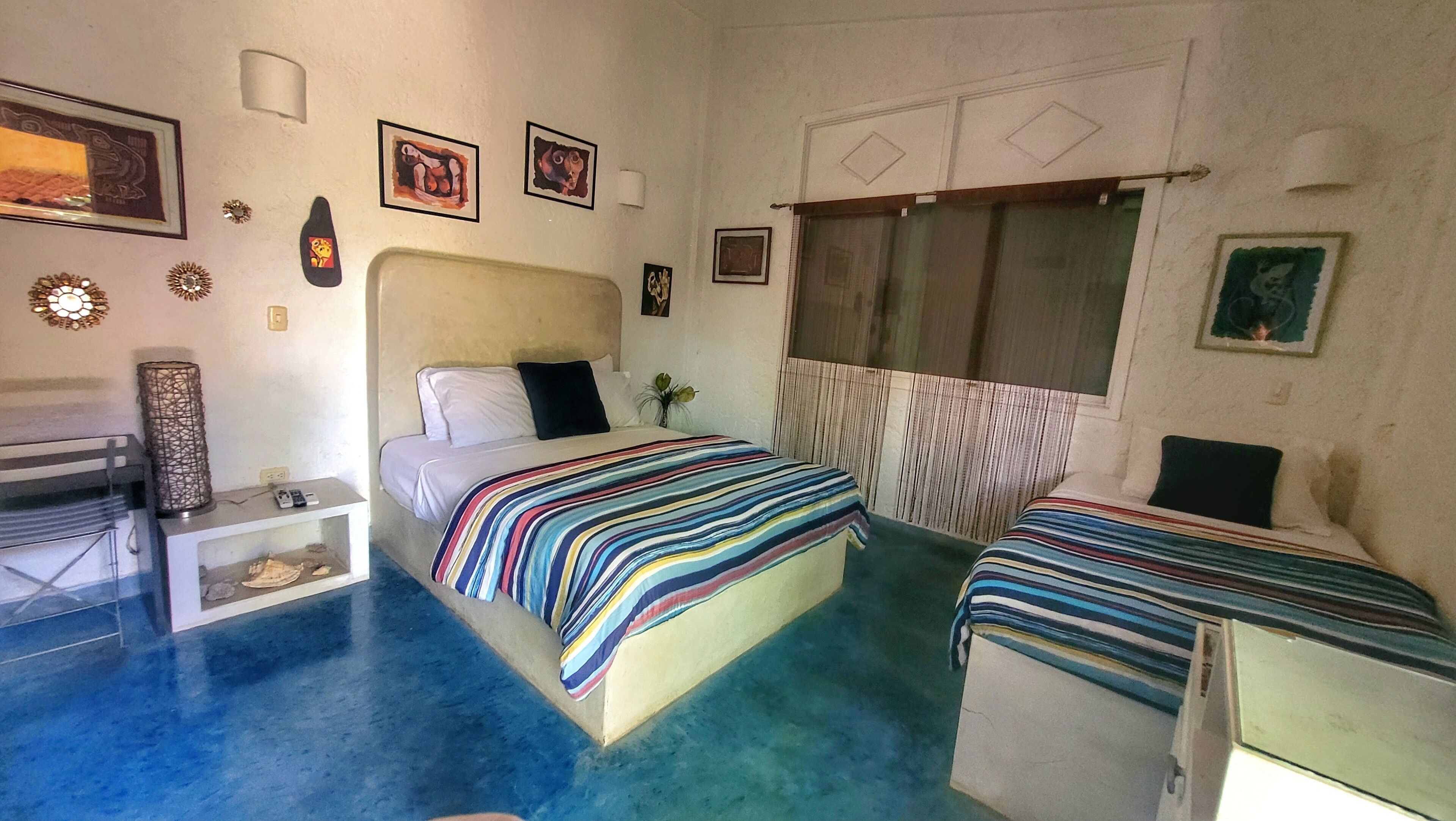 A room with two beds, a desk, a chair, and a window with curtains.