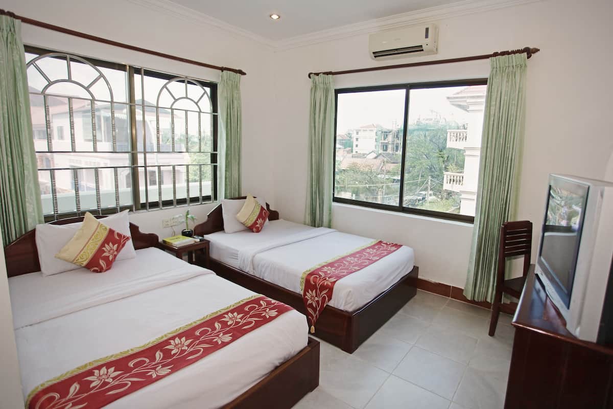 Habitación de hotel con dos camas, televisión y ventanas amplias con cortinas.