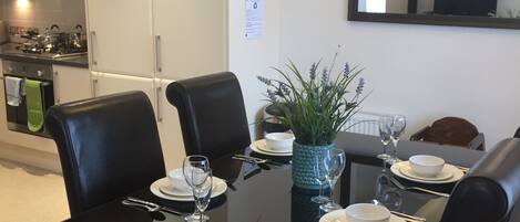 Un comedor moderno con una mesa de vidrio, sillas negras y un centro de mesa con un jarrón azul.