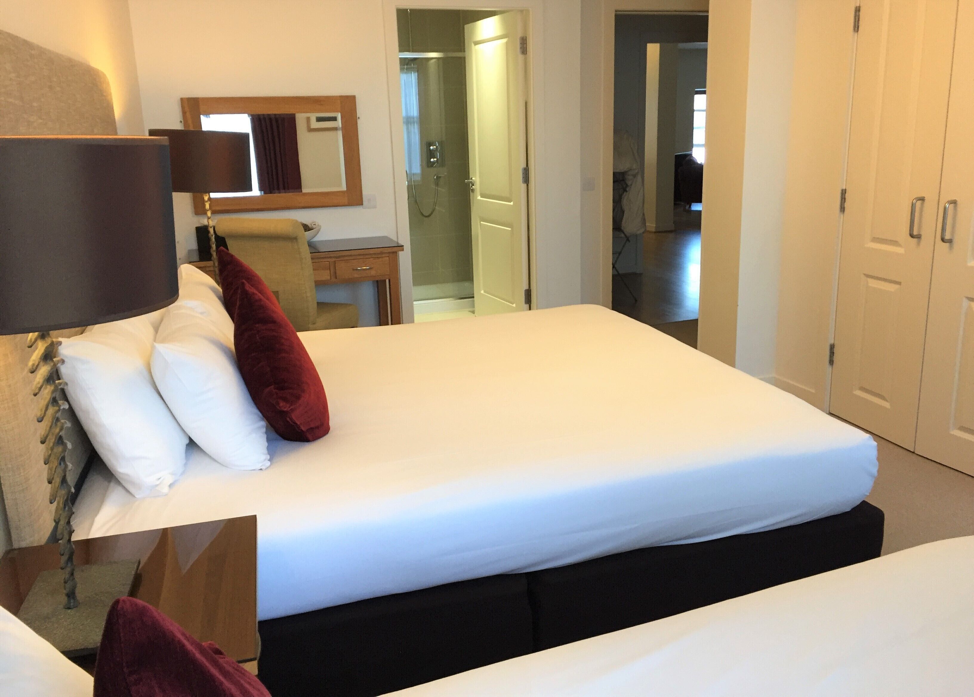 A hotel room with a bed, a desk, a chair, and a wardrobe.