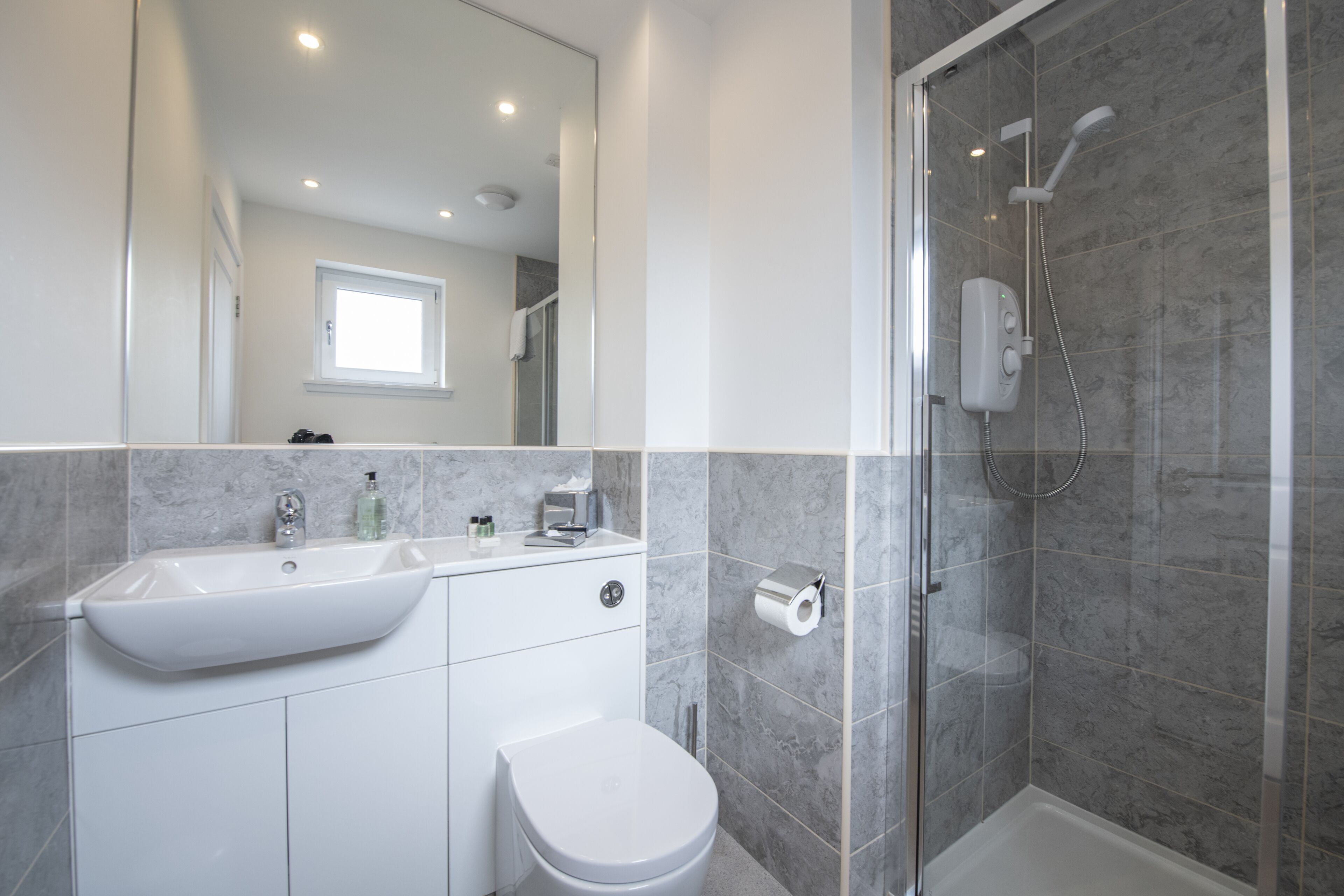 A modern bathroom with a sink, toilet, and shower.