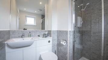 A modern bathroom with a sink, toilet, and shower.