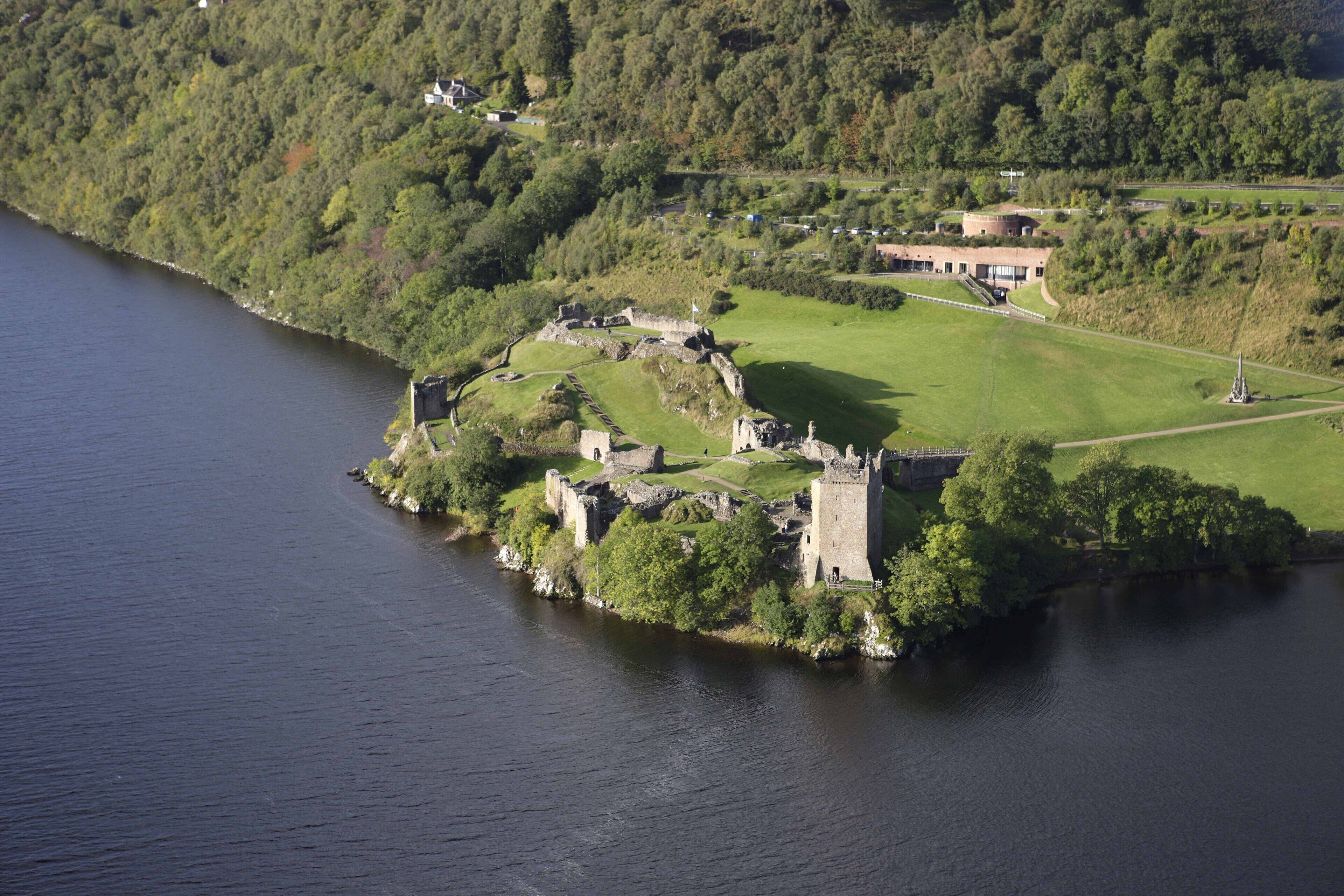 An aerial view of a historic castle surrounded by water and greenery.