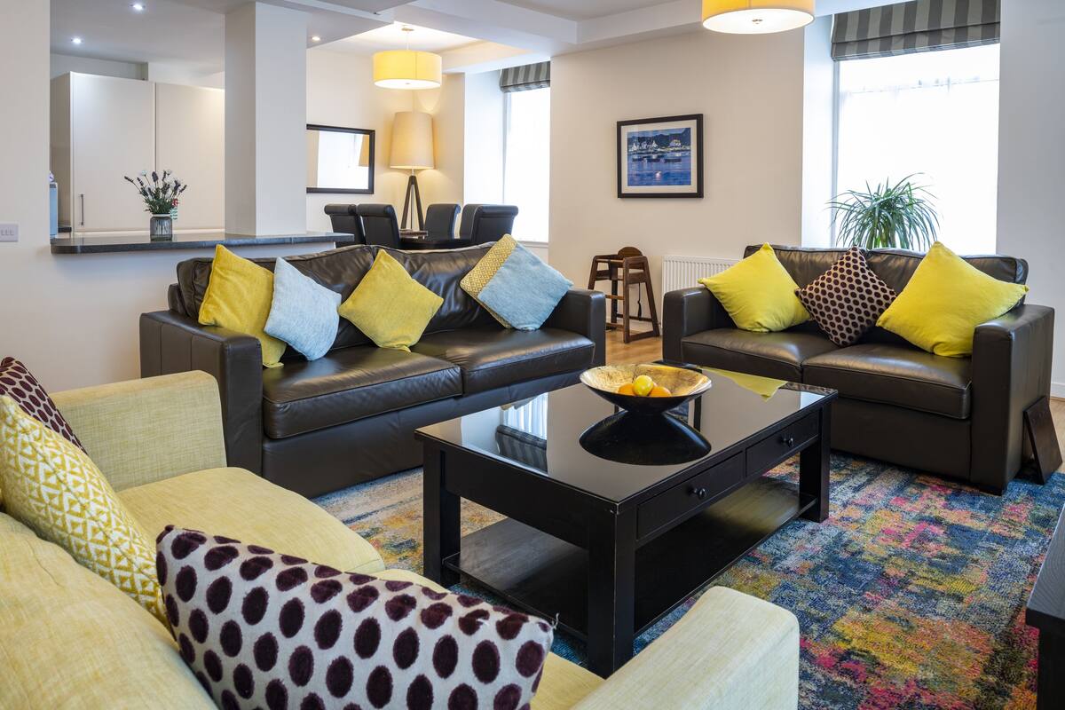 A modern living room with two sofas, a coffee table, and a dining area with chairs.