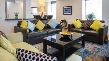 A modern living room with two sofas, a coffee table, and a dining area with chairs.