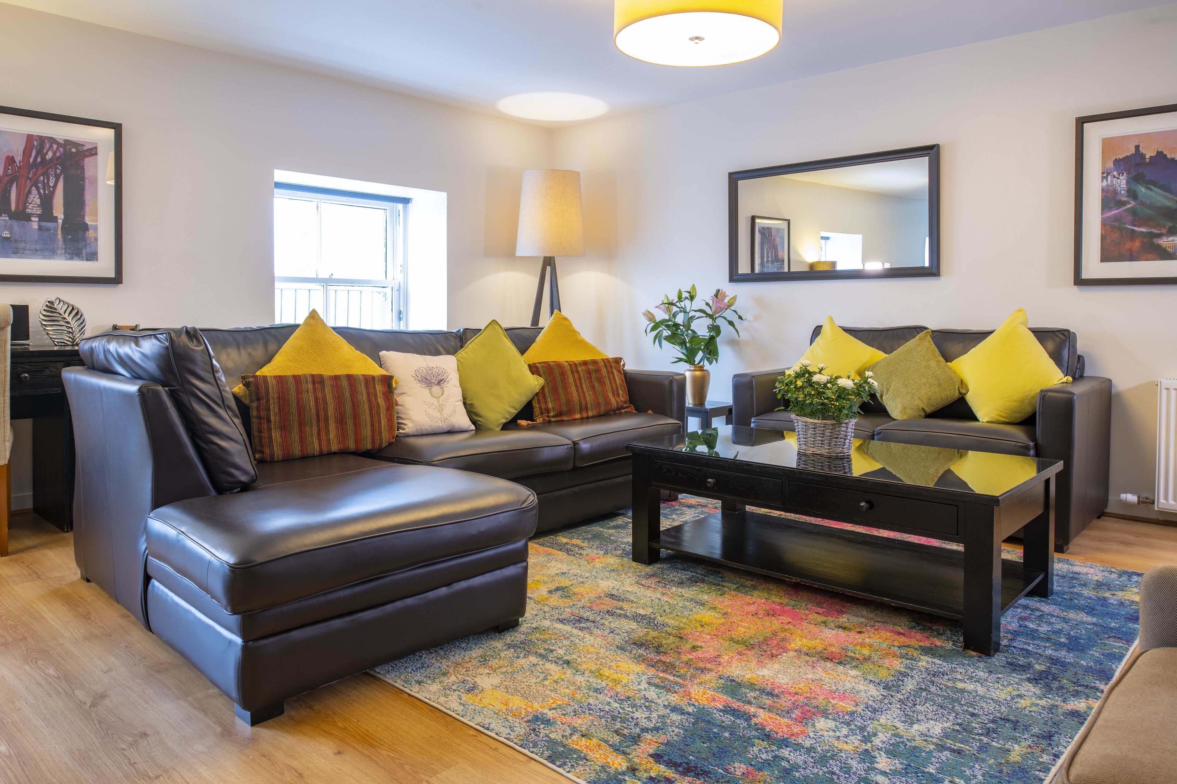 A modern living room with a sectional sofa, a coffee table, and a colorful rug.