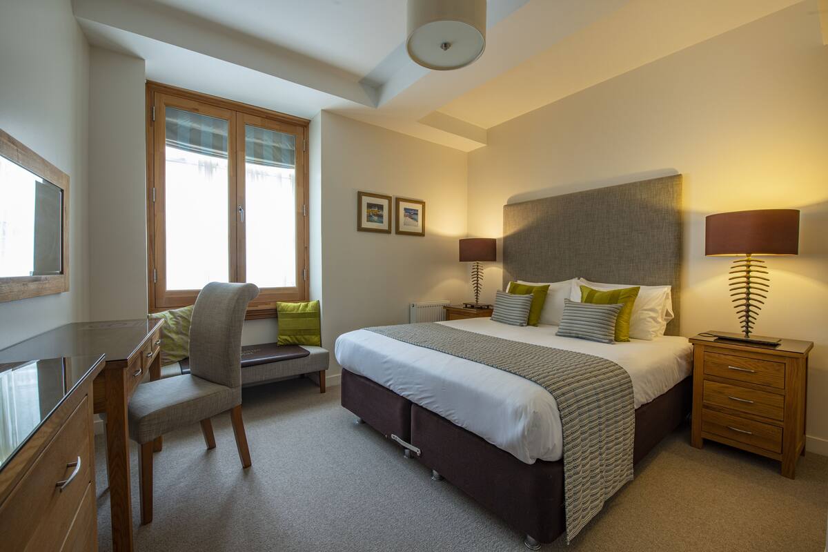 A bedroom with a bed, bedside tables, a desk, and a chair.