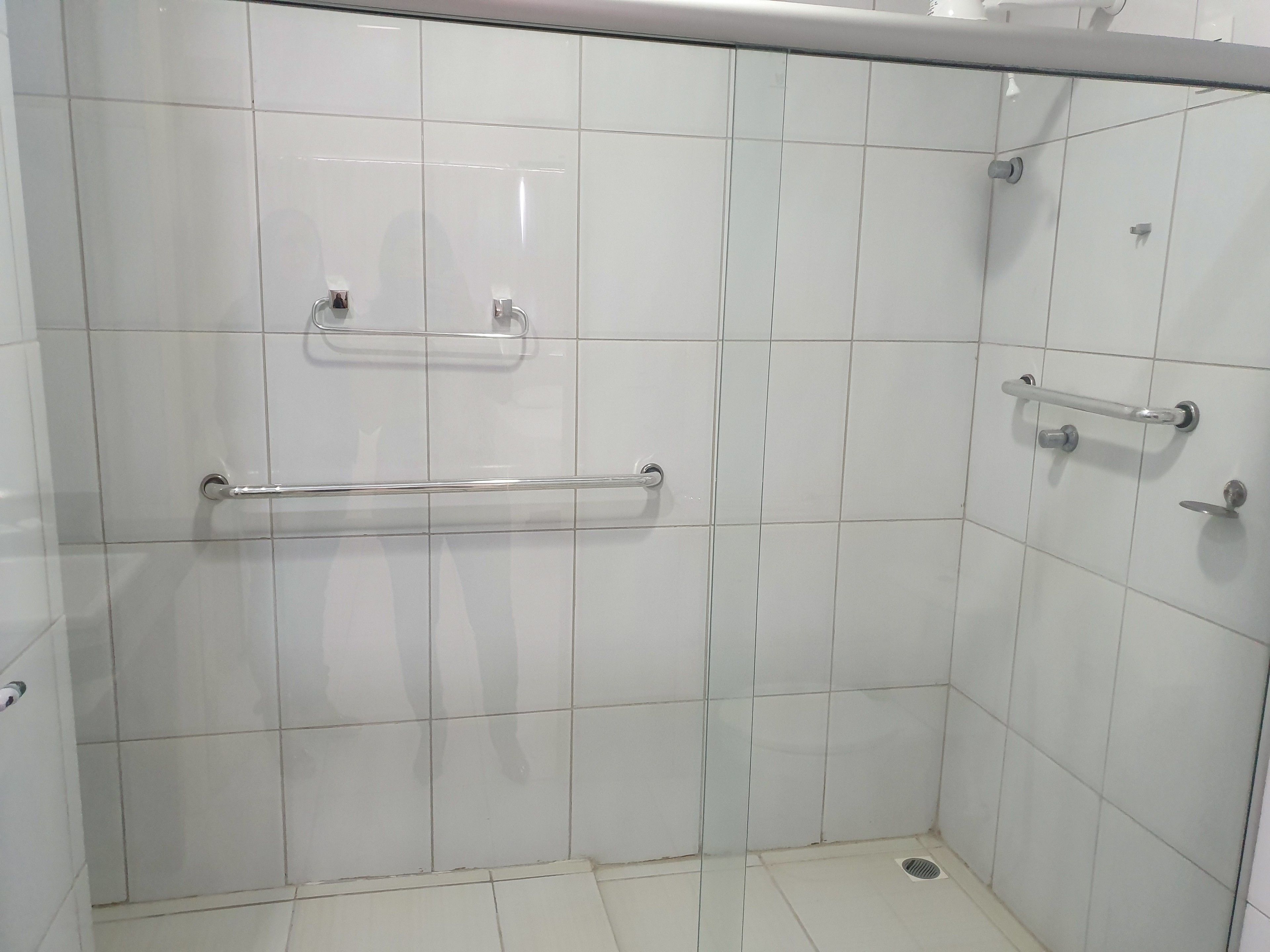 Zona de ducha con azulejos, barras de apoyo y panel de control.