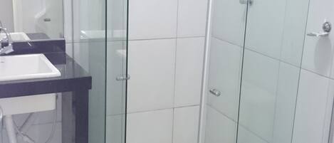 Un baño moderno con cabina de ducha de vidrio, un lavamanos y un inodoro.