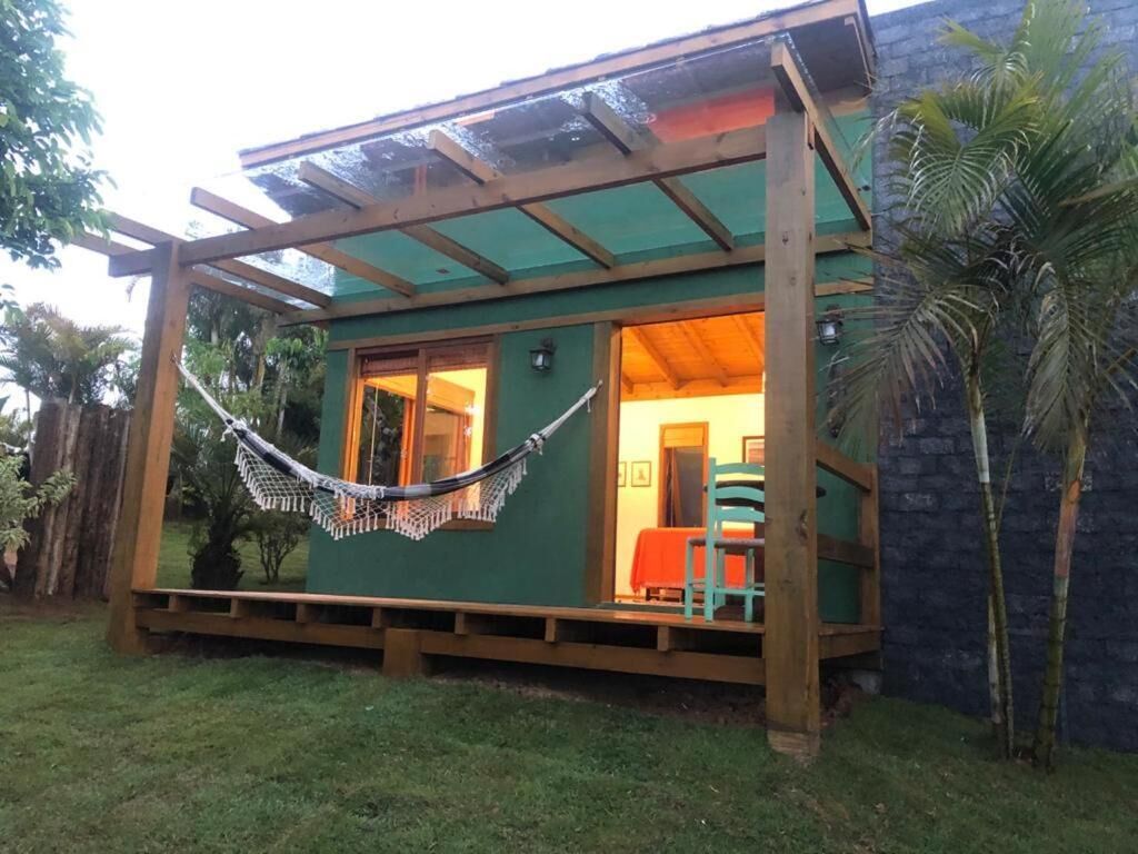 A wooden structure with a covered porch, a hammock, and a small seating area with chairs.