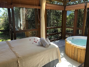 A spa room with a bed, a hot tub, and large windows.