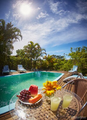 A poolside setting with a clear view of the pool, lounge chairs, and tropical vegetation. - Pousada Watu Kerere (Imbituba)