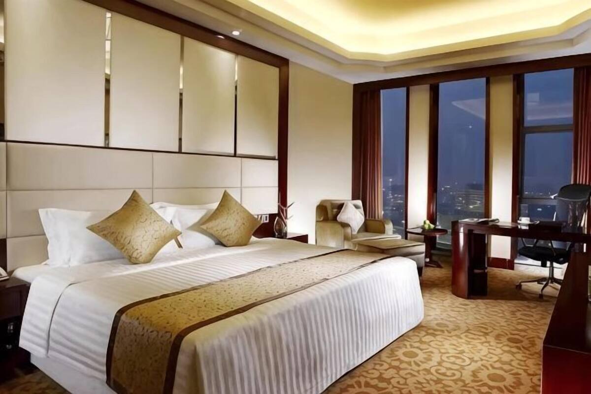Una habitació d'hotel amb un llit gran, un escriptori i vistes a la ciutat.