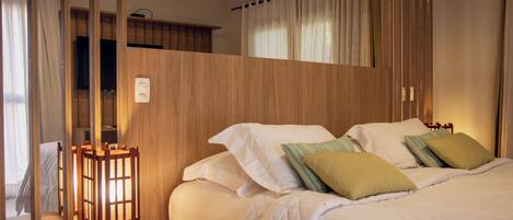 A hotel room with a bed, a nightstand, a lamp, and a wooden partition.