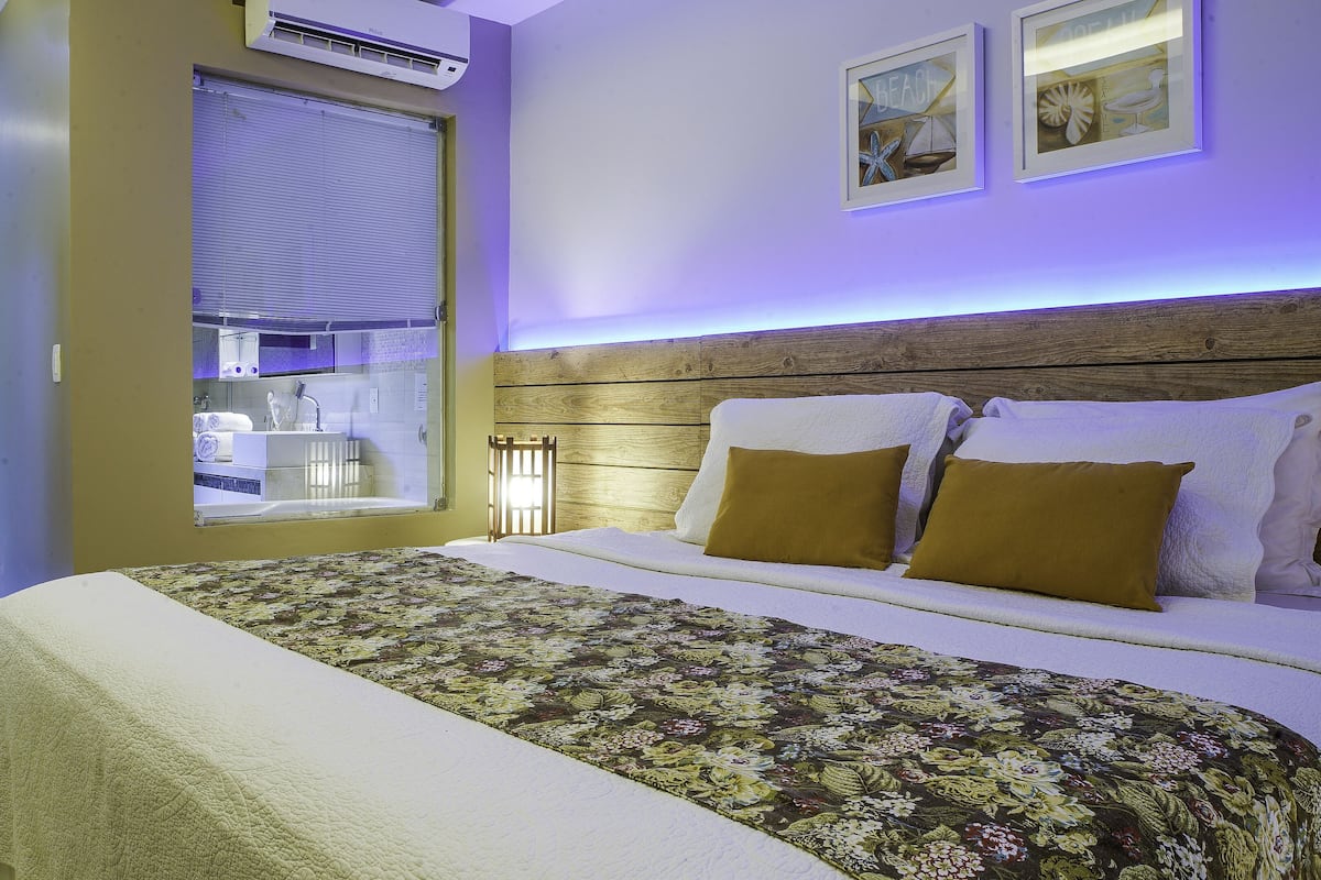 Un dormitorio con una cama grande, un cabecero de madera y una ventana con persianas.