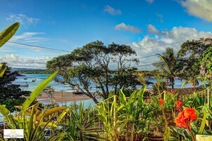 A coastal view with boats, lush greenery, and a clear sky.