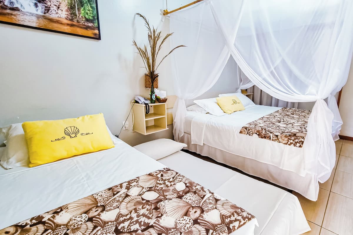 Ein Zimmer mit zwei Betten, jeweils mit Baldachin, einem Nachttisch mit Lampe und einem kleinen Regal mit Dekoration.