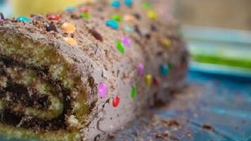 A chocolate roll with colorful sprinkles on a glass plate.