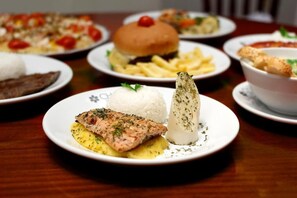 A variety of dishes on plates, including salmon, rice, and a vegetable dish. - Holz Hotel (Joinville)