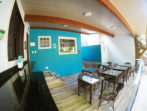 A restaurant with a blue wall, wooden ceiling, and a seating area with tables and chairs. - Pousada Guapuruvu (Angra dos Reis)
