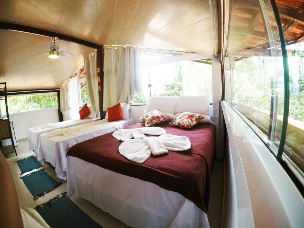 A room with a bed, two bedside tables, a ceiling fan, and a window with curtains.