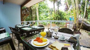 An outdoor dining area with tables and chairs, a breakfast spread including toast, fruit, and a hot beverage. - Pousada Guapuruvu (Angra dos Reis)