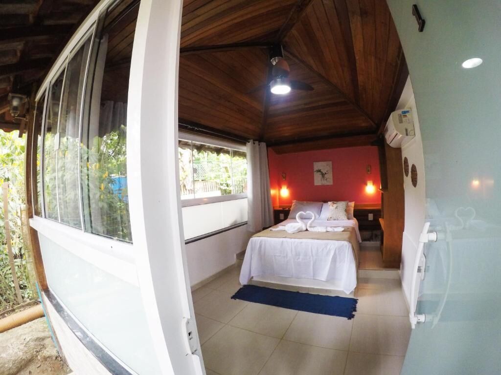 A room with a bed, a window, a ceiling fan, and a wall-mounted light fixture.