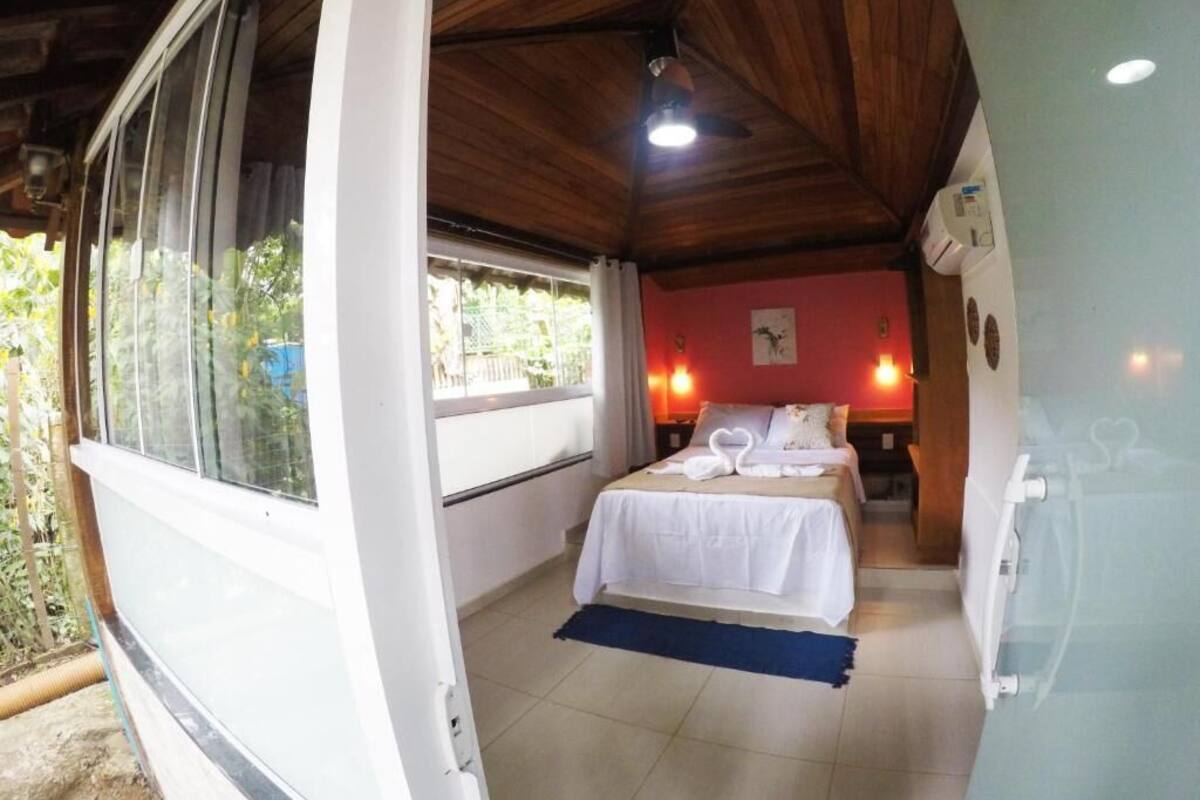 Una habitación con cama, ventana, ventilador de techo e iluminación en la pared.